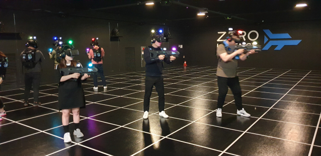부산 중구 남포동 제로레이턴시에서 게이머들이 VR 게임을 즐기고 있다. 밖에서 보면 사람들의 엉성한 동작이 생뚱맞아 보이지만, 지금 게이머들은 VR 세상 속에서 전쟁을 치르고 있는 중이다.