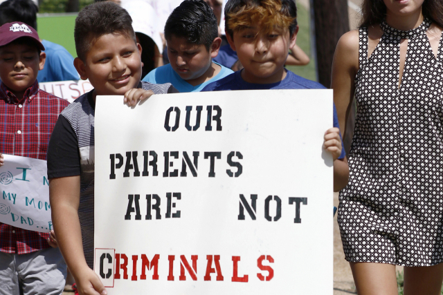 미국 캔턴에서 라틴계 이민자 부모를 둔 아이들이 11일(현지 시간) ‘우리의 부모들은 범죄자가 아니다’라는 글이 새겨진 표지판을 듣고 매디슨 카운티 법원을 향해 행진하고 있다. AP연합뉴스