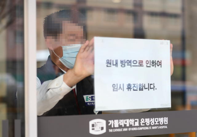 21일 오전 환자이송요원 중 1명이 신종코로나바이러스 감염증(코로나19) 1차 양성 판정을 받은 서울 은평성모병원에서 관계자가 휴진 안내문을 붙이고 있다. 연합뉴스