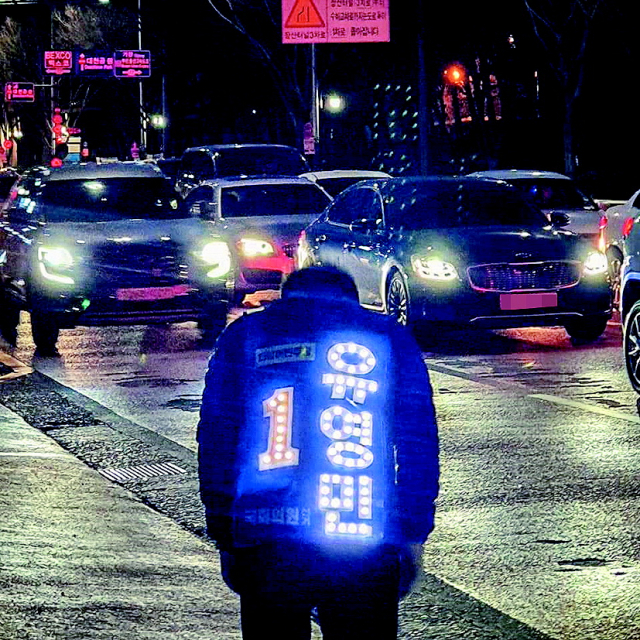 민주당 해운대갑 유영민 후보가 ‘LED 갑옷’ 유세 점퍼를 입고 퇴근길 인사를 하는 모습을 단톡방에 올렸다. 유영민 제공