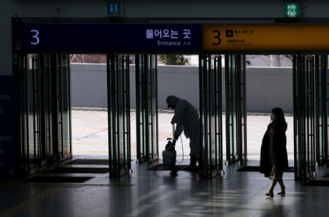 지난 21일 오후 서울역 대합실에서 방역업체 관계자가 출입구 소독 작업을 하고 있다. 연합뉴스