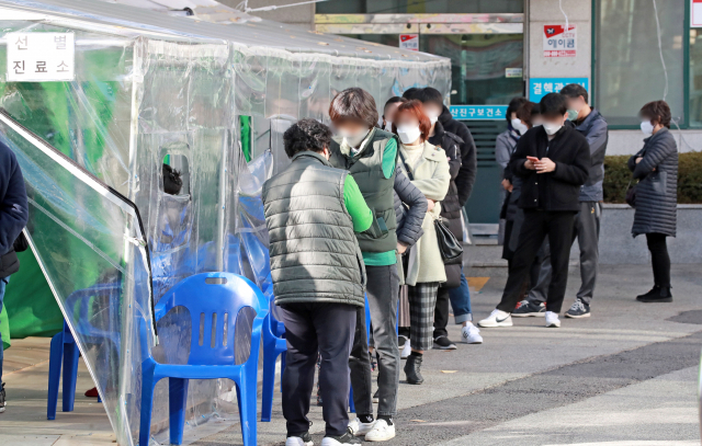 부산지역에 코로나19 확진자가 급증하는 가운데 지난 25일 부산 부산진구보건소 선별진료소에 코로나19 검사를 받으려는 시민들이 길게 줄을 서 있다. 김경현 기자 view@