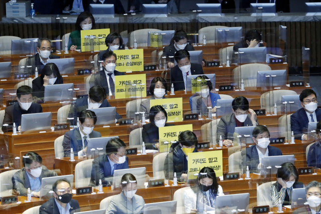 정의당 의원들이 26일 서울 여의도 국회에서 열린 본회의에서 가덕도 관련 법안을 비판하는 피켓을 의석에 붙여 놓고 있다. 연합뉴스
