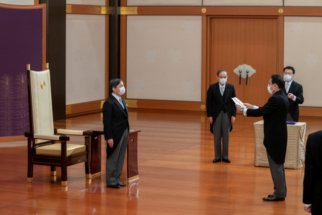 기시다 후미오(오른쪽) 일본 신임 총리가 4일 도쿄 왕궁에서 나루히토(왼쪽) 일왕으로부터 임명장을 받는 친임식(親任式)을 치르고 있다. 왼쪽 두 번째는 스가 요시히데 전 총리. 연합뉴스