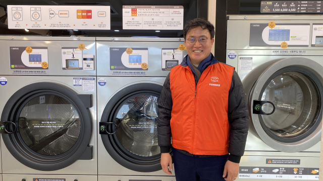 부산연탄은행 강정칠(53) 대표가 취약계층에게 한 달에 한 번 무료로 빨래 서비스를 제공하는 부산 서구 '우리동네빨래방' 앞에서 미소를 보이고 있다. 이상배 기자 sangbae@busan.com