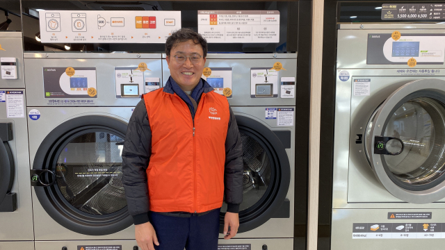 부산연탄은행 강정칠(53) 대표가 취약계층에게 한 달에 한 번 무료로 빨래 서비스를 제공하는 부산 서구 '우리동네빨래방' 앞에서 미소를 보이고 있다. 이상배 기자 sangbae@busan.com