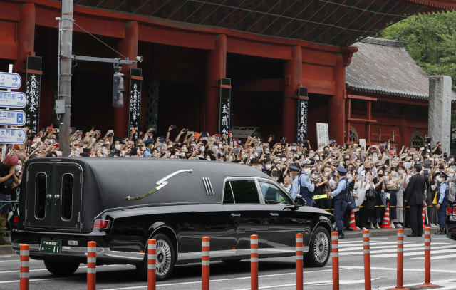 12일 오후 일본 도쿄 내 사찰 '조조지'에서 아베 신조 전 총리 장례식이 끝난 뒤 운구차가 나가는 모습. 많은 시민이 몰려 나와 아베 전 총리를 추모하고 있다. 연합뉴스