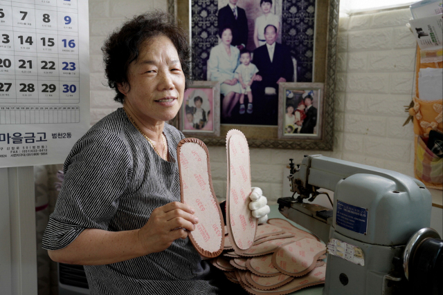 산복빨래방을 찾아와 빨래방 식구들과 웃고 떠드는 어머님은 당시 한국 신발산업을 이끌던 ‘여공’이었다. 사진은 현덕순 어머님이 30년 넘게 부업으로 하고 있는 신발 밑창을 들어보이고 있는 모습.