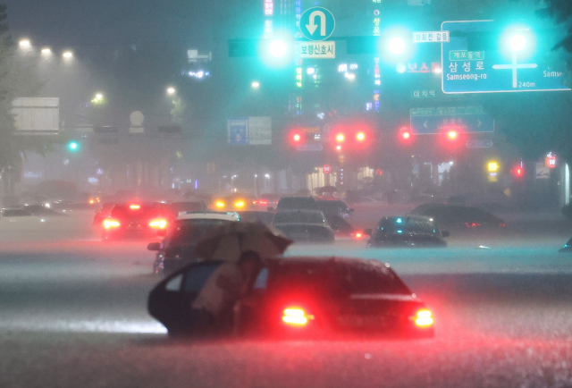 8일 밤 서울 강남구 대치역 인근 도로에서 차량이 침수되자 운전자가 대피하고 있다. 연합뉴스