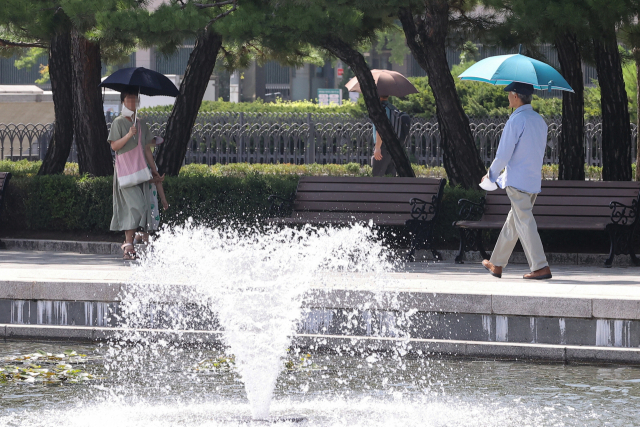 전국에 폭염경보가 내린 지난달 29일 서울 용산구 전쟁기념관에서 시민들이 양산을 쓰고 걷고 있다. 연합뉴스