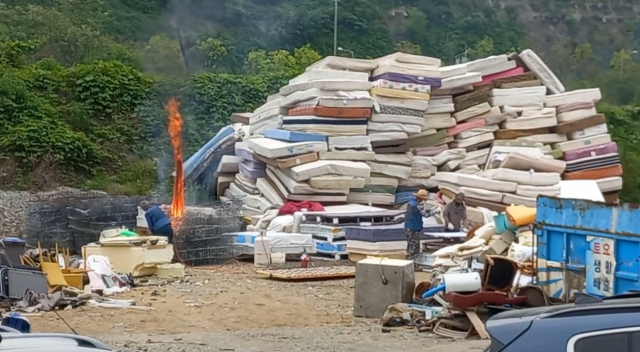 지난 5월 경남 통영시 명정동 환경자원화센터 공터에 야적해 둔 매트리스를 작업자들이 무단으로 소각하고 있다. 통영거제환경운동연합 제공