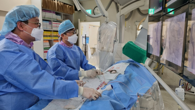김무현 동아대병원 순환기내과 교수(오른쪽)가 협심증 환자에게 막힌 혈관을 뚫기 위해 관상동맥중재술을 시행하고 있다. 동아대병원 제공