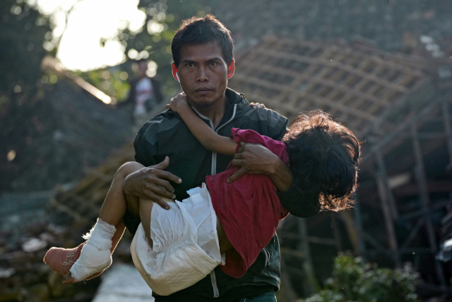 지난달 24일(현지시간) 인도네시아 서자바주 치안주르에서 한 주민이 지진으로 다친 딸을 안고 임시대피소로 가고 있다. 연합뉴스