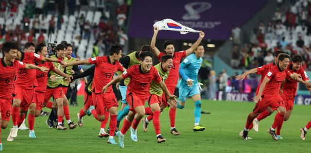 3일 카타르 알라이얀의 에듀케이션 시티 스타디움에서 열린 2022 월드컵 조별리그 H조 3차전에서 포르투갈을 꺾고 16강 진출에 성공한 한국 축구 대표팀 선수들이 태극기와 함께 그라운드를 달리며 기쁨을 만끽하고 있다. 연합뉴스