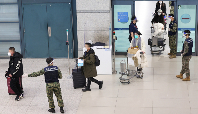 8일 오후 인천국제공항 제1여객티미널을 통해 입국한 중국발 입국자들이 검역지원단의 안내를 받아 이동하고 있다. 연합뉴스