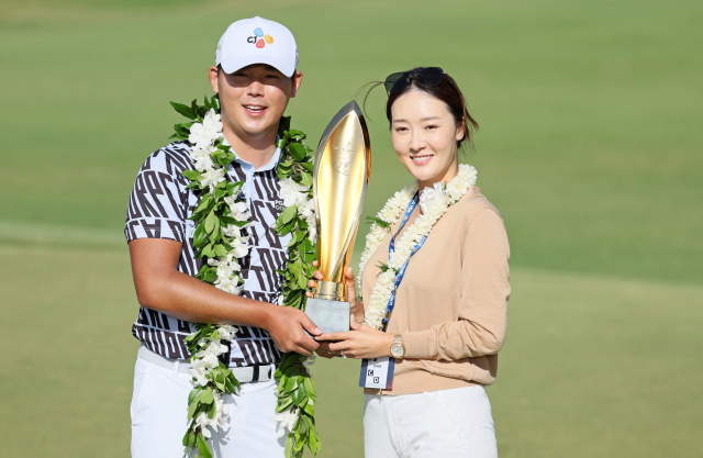 16일(한국시간) 열린 미국프로골프(PGA) 투어 소니오픈에서 우승한 김시우(왼쪽)가 아내 오지현과 함께 우승 트로피를 들고 기뻐하고 있다. 김시우와 KLPGA 투어 선수 출신 골퍼인 오지현은 지난해 12월 결혼했다. AFP연합뉴스