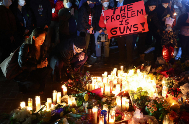 11명이 숨진 미국 캘리포니아 몬터레이 파크의 총기난사 현장에서 24일(현지시간) 촛불 추모집회가 열렸다. 한 추모객이 ‘문제는 총이다’라고 적힌 종이를 들고 있다. AFP연합뉴스