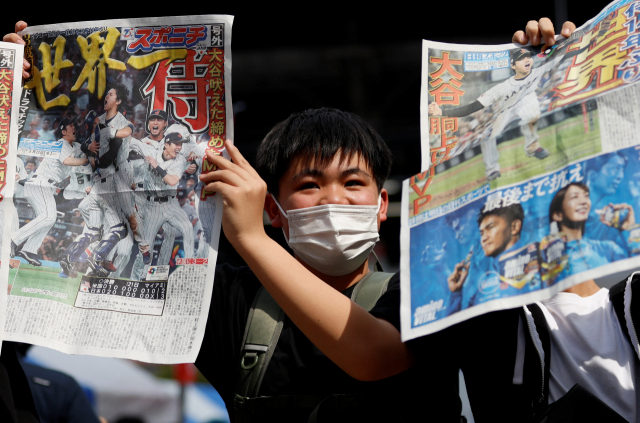 22일 일본 도쿄 거리에서 시민들이 일본의 월드베이스볼클래식 우승 소식을 보도한 호외 신문을 들어보이고 있다. 로이터연합뉴스