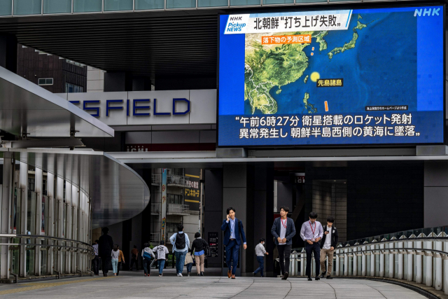 31일 북한의 탄도미사일 발사 관련 뉴스가 나오는 전광판 아래로 일본 도쿄 시민들이 걷고 있다. 이날 오전 일본 정부는 북한의 발사체에 대응해 오키나와 지역에 긴급 대피 명령을 내렸다가 약 30분 만에 해제했다. AFP연합뉴스