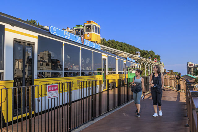 고가 궤도를 달리는 스카이캡슐은 해운대해변열차보다 더 높은 곳에서 해안 경관을 감상할 수 있다. 아래는 해운대해변열차 곁을 지나는 외국인 관광객들. 해운대블루라인파크 제공