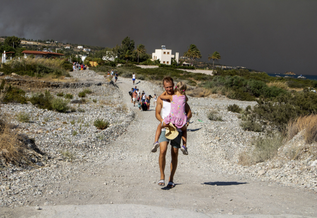 22일 그리스 로도스섬에서 한 남성이 여자 아이를 안고 대피하고 있다. 이 섬에서는 큰 산불이 발생해 주민, 관광객 등 3만여 명이 대피했다. AP연합뉴스연합뉴스