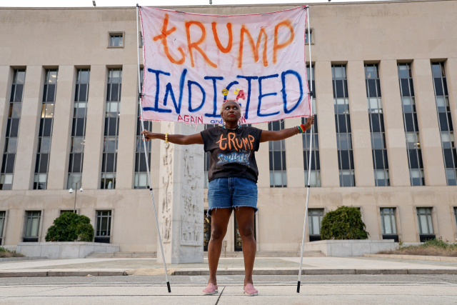 1일 미 워싱턴DC 연방법원 앞에서 한 시민이 ‘트럼프 기소’라고 적힌 현수막을 들고 있다. 로이터연합뉴스