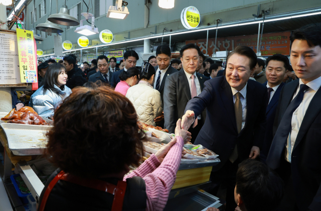 윤석열 대통령이 22일 경남 창원시 마산합포구 마산어시장을 찾아 상인들과 인사를 나누고 있다. 연합뉴스