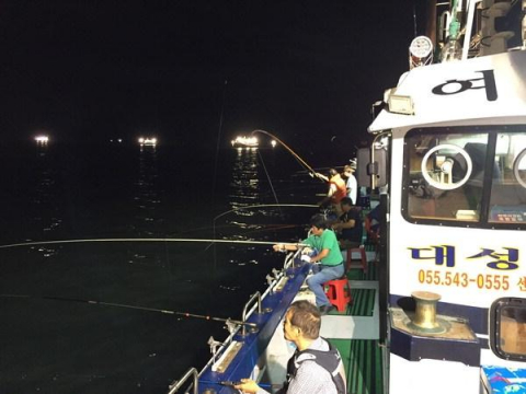 여명호 선상에서 진해만을 환하게 밝힌 갈치 낚싯배들을 배경으로 낚시하고 있다.