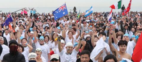 5~6일 부산 해운대해수욕장에서 세계 최고의 겨울바다 이벤트인 제32회 해운대 북극곰축제가 열린다. 사진은 지난해 1월 북극곰 수영축제 참가자들이 각국 깃발을 흔들며 공연에 맞춰 몸을 풀고 있는 모습. 부산일보DB