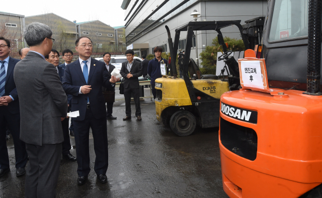 홍남기 부총리 겸 기획재정부 장관이 18일 미세먼지 저감 관련 현장방문으로 경기도 파주시 소재 (주)이알인터내셔널을 방문해 관계자로부터 건설기계 엔진교체에 따른 매연저감량과 성능 설명을 듣고 있다. 기재부 제공