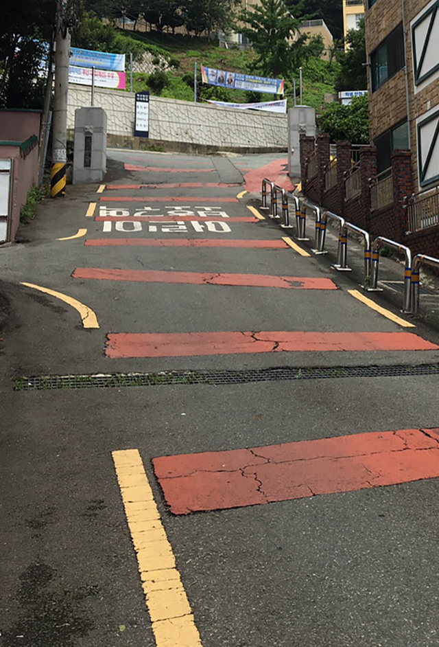 부산 사하구 건국중·고등학교로 향하는 진입도로. 이 도로는 좁은 폭과 가파른 경사 구조로 도로시설 기준에 맞지 않아 학부모와 인근 주민들이 안전 대책을 촉구하고 있다.