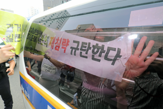 22일 오후 부산 동구 초량동 일본영사관에 진입해 반일 투쟁 시위를 벌이던 대학생 6명이 경찰에 연행되고 있다. 이들은 이날 오전 11시부터 일본 영사관 안 도서관에 신분증을 제출하고 미리 들어가 있다가 오후 2시 30분께 영사관 마당으로 뛰어나가 ‘주권침탈 아베규탄’ 플래카드에 페트병을 달아 밖으로 던진 혐의를 받고 있다. 김경현 기자 view@