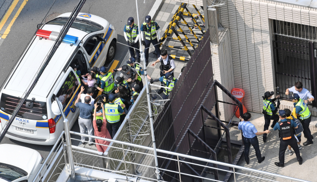 22일 오후 부산 동구 초량동 일본영사관에 진입해 반일 투쟁 시위를 벌이던 대학생 6명이 경찰에 연행되고 있다. 이들은 이날 오전 11시부터 일본 영사관 안 도서관에 신분증을 제출하고 미리 들어가 있다가 오후 2시 30분께 영사관 마당으로 뛰어나가 ‘주권침탈 아베규탄’ 플래카드에 페트병을 달아 밖으로 던진 혐의를 받고 있다. 김경현 기자 view@