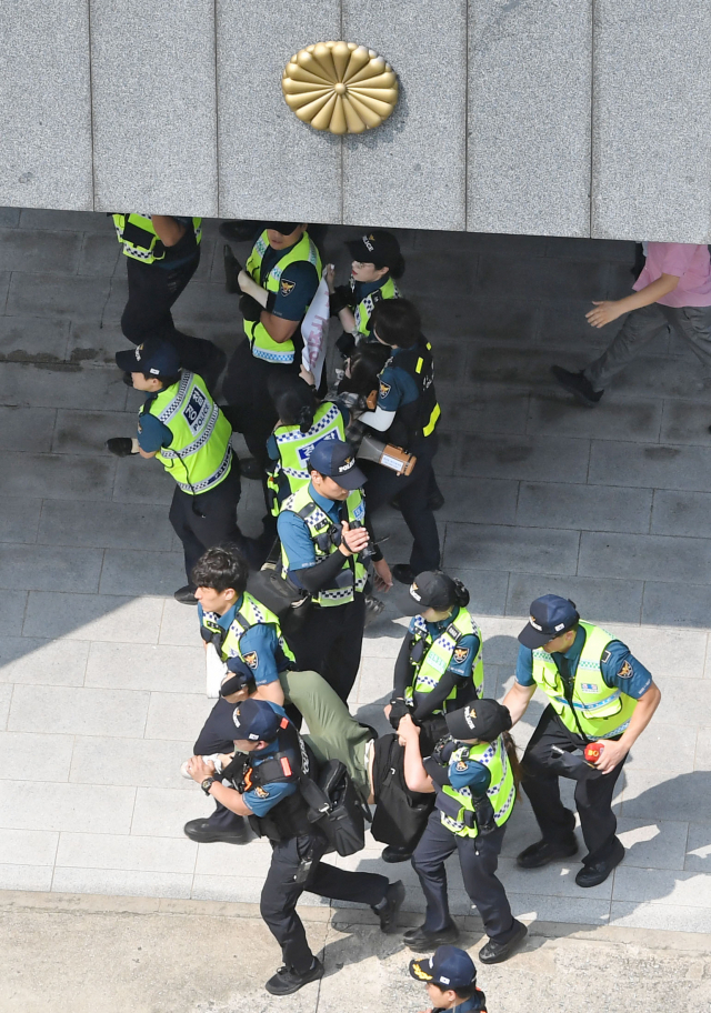 22일 오후 부산 동구 초량동 일본영사관에 진입해 반일 투쟁 시위를 벌이던 대학생 6명이 경찰에 연행되고 있다. 이들은 이날 오전 11시부터 일본 영사관 안 도서관에 신분증을 제출하고 미리 들어가 있다가 오후 2시 30분께 영사관 마당으로 뛰어나가 ‘주권침탈 아베규탄’ 플래카드에 페트병을 달아 밖으로 던진 혐의를 받고 있다. 김경현 기자 view@