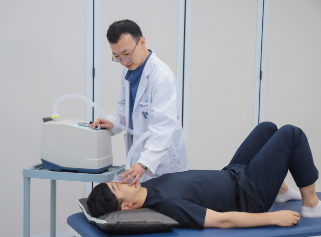 최우혁 과장이 가래를 제거하는 기침유발기로 호흡재활치료를 하고 있다. 부산의료원 제공