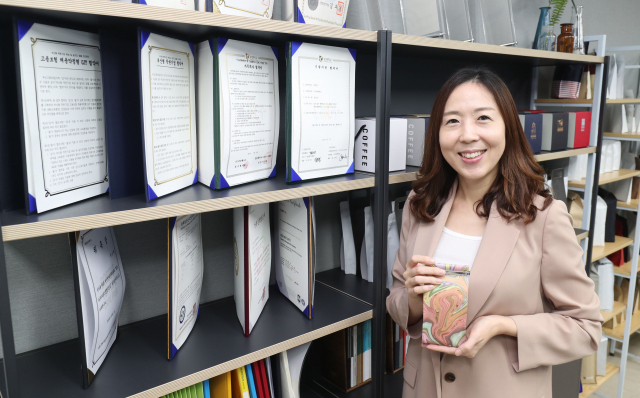 지난 11일 부산 수영구 광안동 코아트 사무실에서 최소형 대표가 대표 상품인 ‘커피앤아트 컬러백’을 들고 회사 소개를 하고 있다. 코아트는 고객의 주문 사항을 반영해 색다른 디자인의 커피 봉투를 제작·판매하는 중소기업이다. 김경현 기자 view@