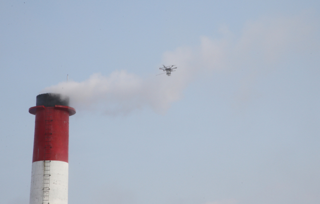 전북지방환경청이 9일 오전 전북 전주시 덕진구의 한 지상 주차장에서 드론 등 첨단장비를 활용한 미세먼지 배출 감시 시연을 했다. 사진은 드론이 굴뚝에서 나오는 배출가스를 채집 중인 모습. 연합뉴스