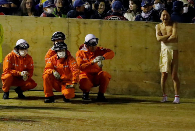 하다카마쓰리에 참가한 훈도시 차림의 남성과 그 옆에서 마스크를 쓰고 응급상황에 대비 중인 인력들(사진=로이터/연합뉴스)
