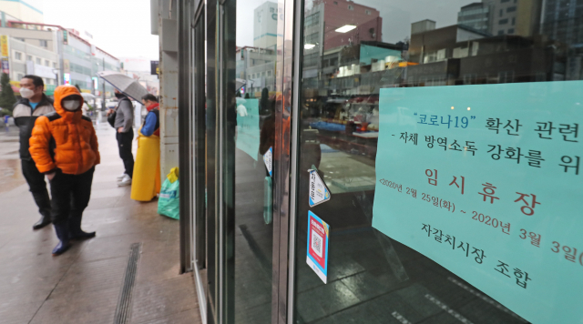 코로나19가 확산 중인 25일 임시 휴장에 들어간 부산 중구 자갈치시장 현대화건물 출입구에 안내문이 붙어있다. 자갈치 어패류조합은 코로나19 확산 차단을 위해 70년 만에 처음으로 자갈치시장 현대화건물 1~2층의 영업을 중단하는 임시 휴장에 들어갔다고 밝혔다. 김경현 기자 view@