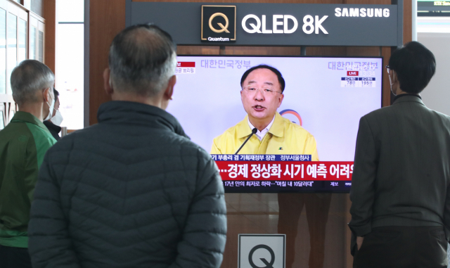 30일 오후 서울역에서 시민들이 비상경제회의 결과 관계부처 합동브리핑을 보고 있다. 연합뉴스