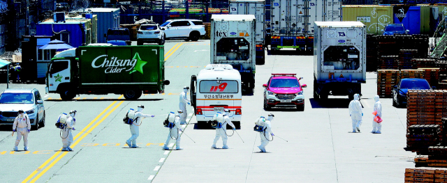 지난 23일 부산 감천항에서 방역 요원들이 코로나19 확진자 16명이 나온 아이스 스트림호 주변 부두를 소독하고 있다. 정종회 기자