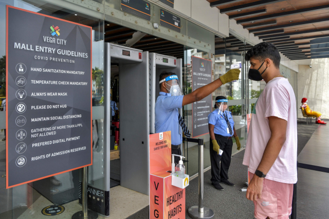 인도 방갈로르의 한 쇼핑몰에서 보안 요원이 고객의 체온을 측정하고 있다. AFP·연합뉴스