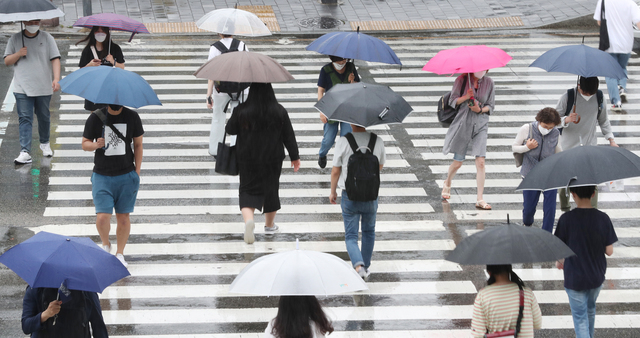 지난 6월 25일 부산지역에 비가 내리는 가운데 코로나19로 인해 마스크를 끼고 우산을 쓴 시민들이 부산역 앞 횡단보도를 건너고 있다. 강선배 기자 ksun@