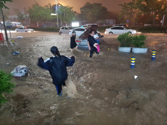 부산지역에 호우경보가 내린 지난 23일 오후 부산 동구 중앙대로가 폭우에 잠겨 차가 침수되자 운전자가 가족을 안고 차에서 빠져나오고 있다. 김경현 기자 view@