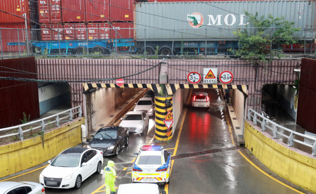 지난 2020년 내린 폭우 때 차량에 갇힌 3명이 목숨을 잃었던 부산 동구 초량제1지하차도에서 경찰과 동구청 관계자들이 상황을 주시하고 있다. 부산일보DB