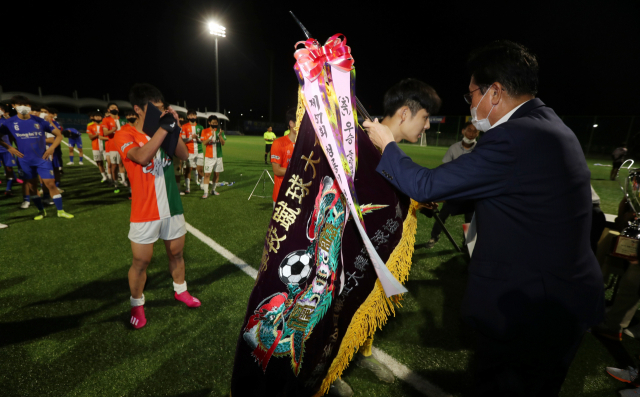 제57회 청룡기 전국 고교축구대회에서 우승한 서울 중대부고 선수들이 13일 고성군 스포츠타운 축구장에서 김진수 부산일보 사장으로부터 우승기를 전달받고 있다. 정대현 기자 jhyun@