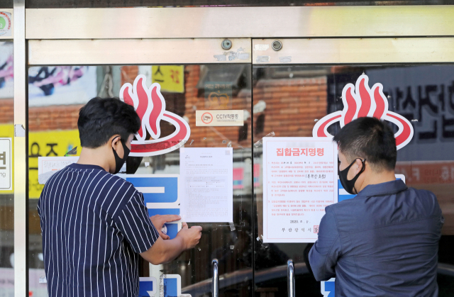 부산시가 부산 전역 목욕탕을 비롯한 고위험시설에 대해 집합금지 명령을 내린 가운데 5일 오후 부산 동구청 직원들이 관내 목욕탕에 집합금지 행정명령 안내문을 붙이고 있다. 김경현 기자 view@