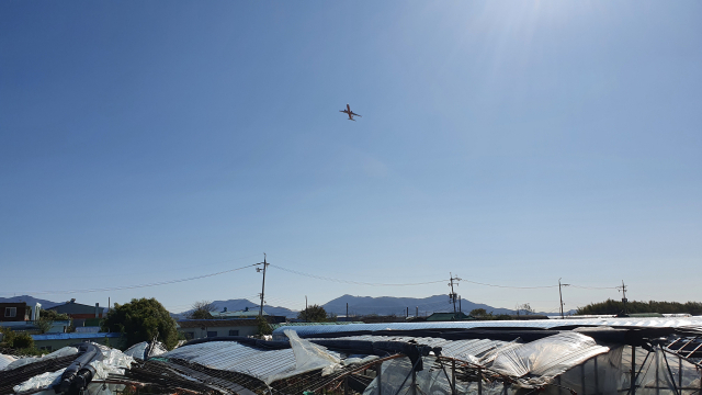 3일 오전 11시 30분께 부산 김해공항에서 이륙해 강서구 강동동 딴치마을 상공을 날아가는 비행기 모습. 최근 딴치마을 주민들은 정부를 상대로 항공기 소음 피해 손해배상 소송을 내 항소심에서 승소했다.