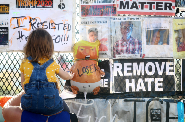 9일(현지시간) 미국 워싱턴DC 백악관 앞에서 한 어린이가 펜스에 걸려 있는 ‘아기 트럼프’ 풍선 인형을 만지고 있다. 풍선에는 ‘패배자’란 글씨가 쓰여져 있다. 로이터연합뉴스