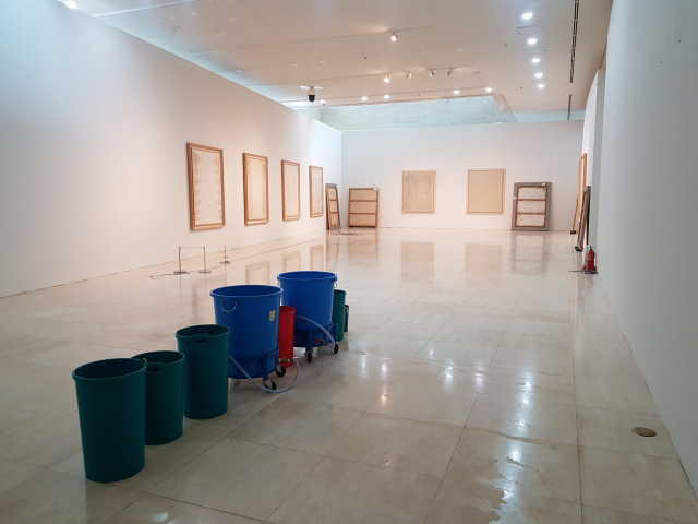 올 8월 폭우로 부산시립미술관 2층 복도에 누수가 발생하자 쓰레기통으로 빗물을 받고 있다. 이로 인해 당시 ‘1960-70년대 부산미술’전 김홍석 작가 특별 전시 코너가 폐쇄되는 소동을 빚었다. 부산시립미술관 제공